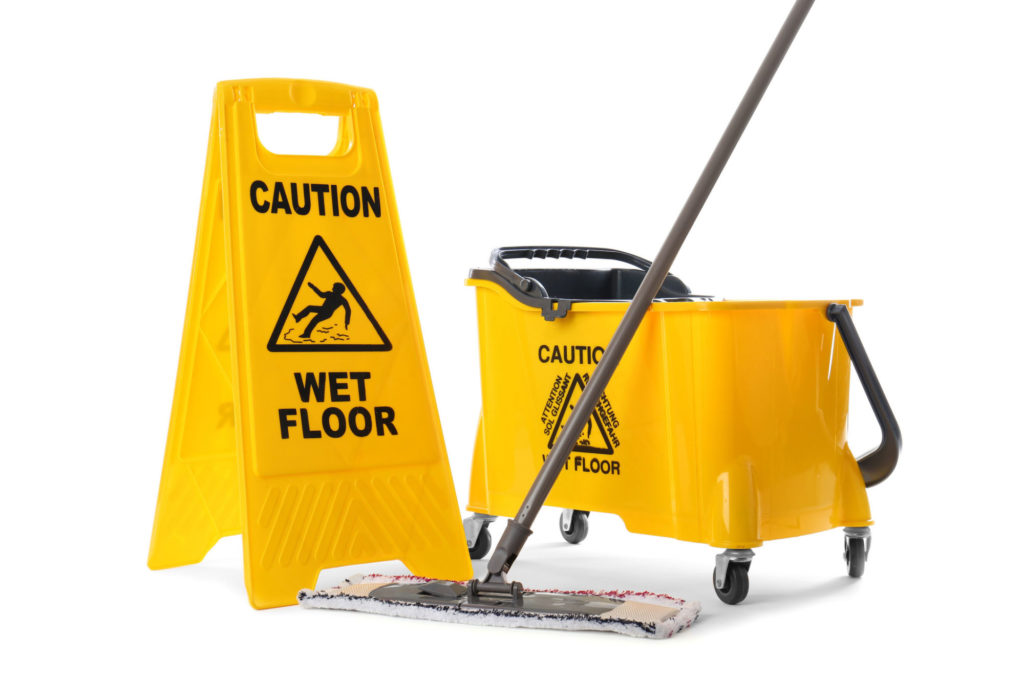 Yellow mop, bucket on wheels and caution wet floor sign