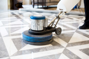 Worker polishing stone floor in modern office building with a closeup of polisher